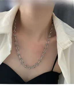 Detailansicht der silbernen Knotenkette auf einem Model mit schwarz-weißer Kleidung