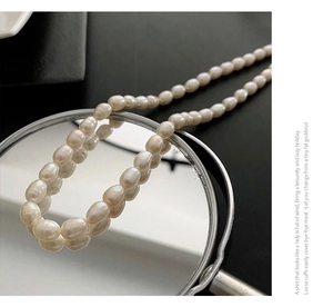 Macro shot of natural Baroque freshwater pearls necklace on a reflective mirror base