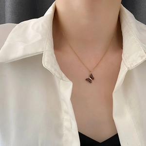 Elegante collana dorata con ciondolo a farfalla in cristallo marrone traslucido su modella