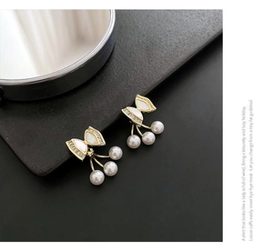 Detail of gold bow earrings featuring sparkling crystals and dangling white pearls on leather