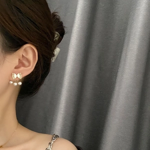 Elegant gold bow earrings with three pearl drops worn on a model against a soft background
