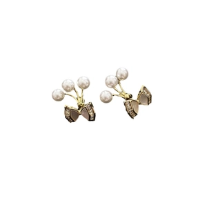 Elegant gold bow earrings with white pearls and zircons on a white background