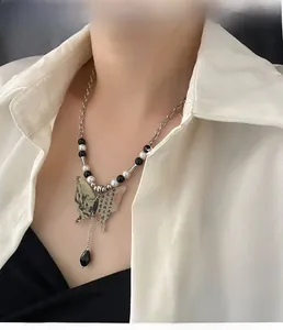 Détail du collier papillon avec motif paysage et chaîne en perles sur modèle