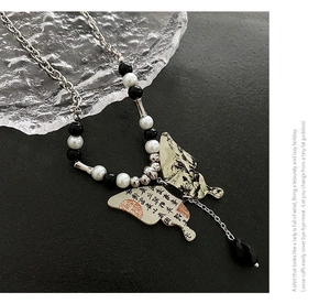 Détail du collier de perles avec pendentif papillon et motifs de peinture à l'encre