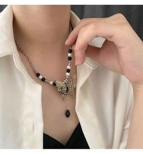Détail du pendentif papillon avec peinture à l'encre et collier à pompons à franges