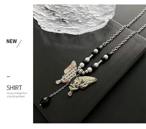 Détail du pendentif papillon avec peinture à l'encre et pompon en métal argenté