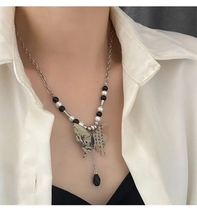 Détail du pendentif papillon avec peinture à l'encre et pompon sur un collier élégant