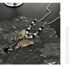 Détail du pendentif papillon avec calligraphie chinoise et breloque en goutte