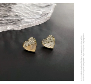 Detail der Herz-Ohrstecker mit Zirkonia und weißem Perlmutt-Inlay auf schwarzem Grund