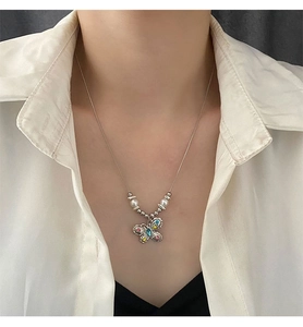 Detailed shot of silver butterfly necklace featuring colorful gemstones and pearl accents
