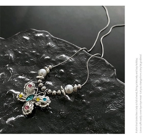 Close-up of butterfly pendant with colorful gemstones and pearls on a snake chain