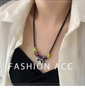 Détail du pendentif cœur avec cadre noir, cristal et touches de vert néon et rose
