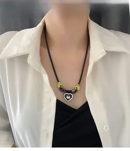 Détail du collier pendentif cœur argenté avec perles vert néon et cordon noir