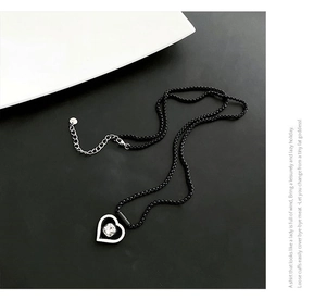 Détail du pendentif cœur argenté avec pierre ronde sur collier de perles noires