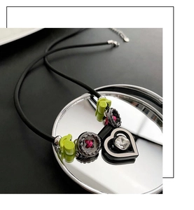 Vue macro du collier pendentif coeur avec note verte et détails de couture roses