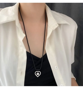 Détail d'un collier double cœur minimaliste avec pierre claire sur une chaîne à billes noire