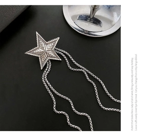 Detailed view of a vintage silver star brooch with textured finish and metal tassel chains