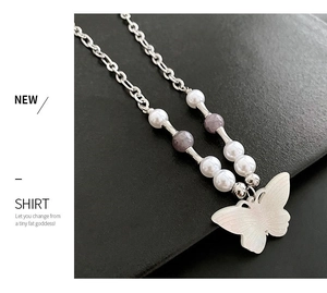 Detail of white butterfly pendant necklace with pearls and purple stone beads on leather