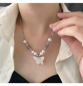 Close-up of a white butterfly pendant necklace with purple beads and silver chain