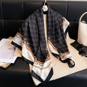 Detailed close-up of a luxury silk scarf featuring elegant chain motifs and letter patterns