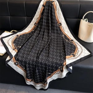 Detailed view of silk square scarf featuring gold chain prints and monogram patterns