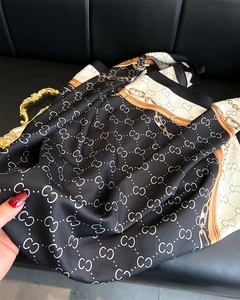 Close-up of silk scarf showing glossy texture and elegant gold chain pattern