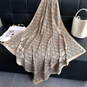 Pañuelo de seda de lujo de 90cm con estampado geométrico sobre sofá de cuero negro