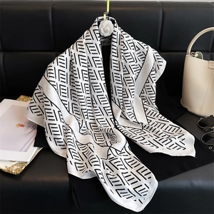 Elegante pañuelo de seda de 90cm con estampado geométrico sobre un sofá de cuero