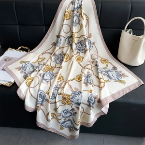 Détail d'un foulard en soie de 90 cm avec motifs de camélia, chaînes dorées et perles chic