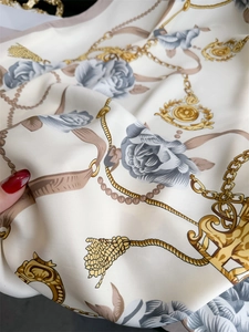 Détail d'un foulard en soie camélia vintage avec chaînes dorées et motifs floraux