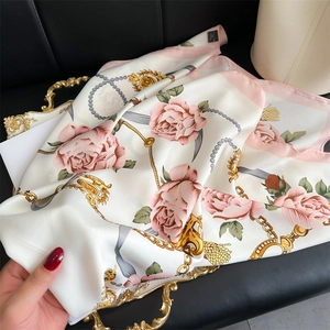 Détail macro d'un foulard en soie avec chaîne dorée et motifs de roses roses