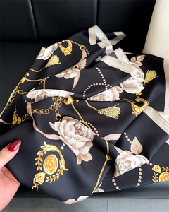 Détail d'un foulard en soie montrant un motif de roses blanches et de chaînes dorées sur noir