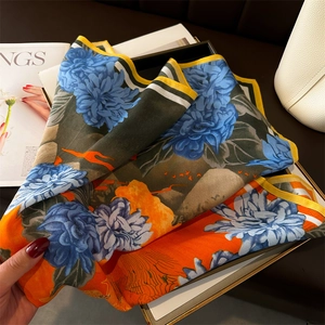 Detail of silk square scarf featuring vibrant blue peony floral prints and orange patterns