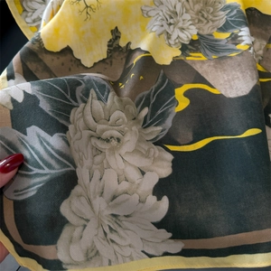 Close-up of soft twill silk scarf showing yellow peony floral pattern and smooth texture