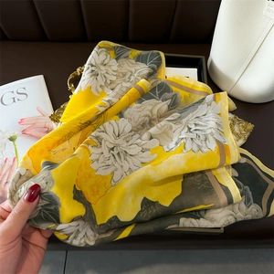 Detail of yellow floral silk scarf with peony print on a golden tray background