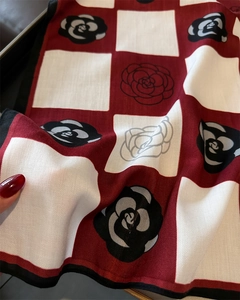 Close-up of red and white checkered silk scarf with camellia pattern and twill texture