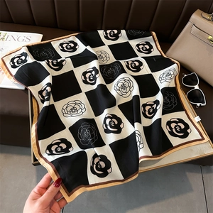Detail of camellia flower and checkerboard silk scarf styled with luxury accessories