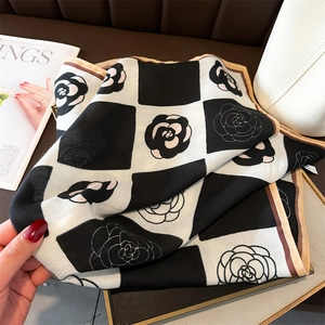 Detail view of checkerboard silk scarf with camellia floral patterns on a luxury tray