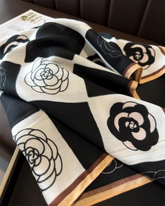 Detail of checkered camellia silk scarf with contrast rolled edges on leather surface