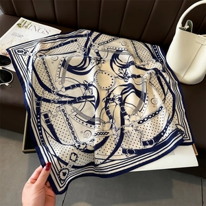 Detailed equestrian print on a navy silk-like square scarf with belt and chain patterns