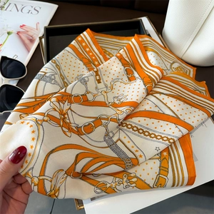 Macro view of silk scarf with vintage equestrian chain patterns and orange borders