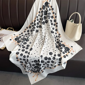 Close-up of silk scarf with floral camellia patterns and golden chain on a sofa