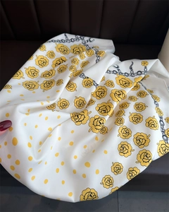 Close-up of a white silk scarf with yellow floral prints and chain patterns