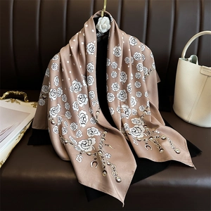 Polka dot camellia silk scarf with gold chains and pearls on a premium display