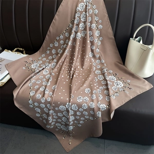 Detailed texture of silk scarf featuring camellia and chain patterns in khaki brown