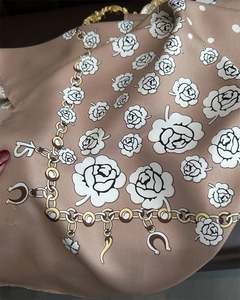 Detail of silk-like scarf featuring camellia flowers and golden chain motifs on beige