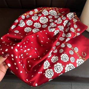 Detail of red silk scarf with white roses, polka dots and golden chain patterns
