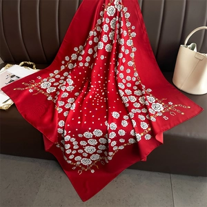 Close-up of red floral silk scarf with polka dots and gold chain pattern on leather