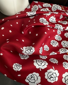 Detail of red silk scarf showing white rose line art and polka dot pattern texture