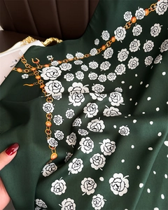 Detail of dark green silk scarf with floral rose pattern and golden chain print